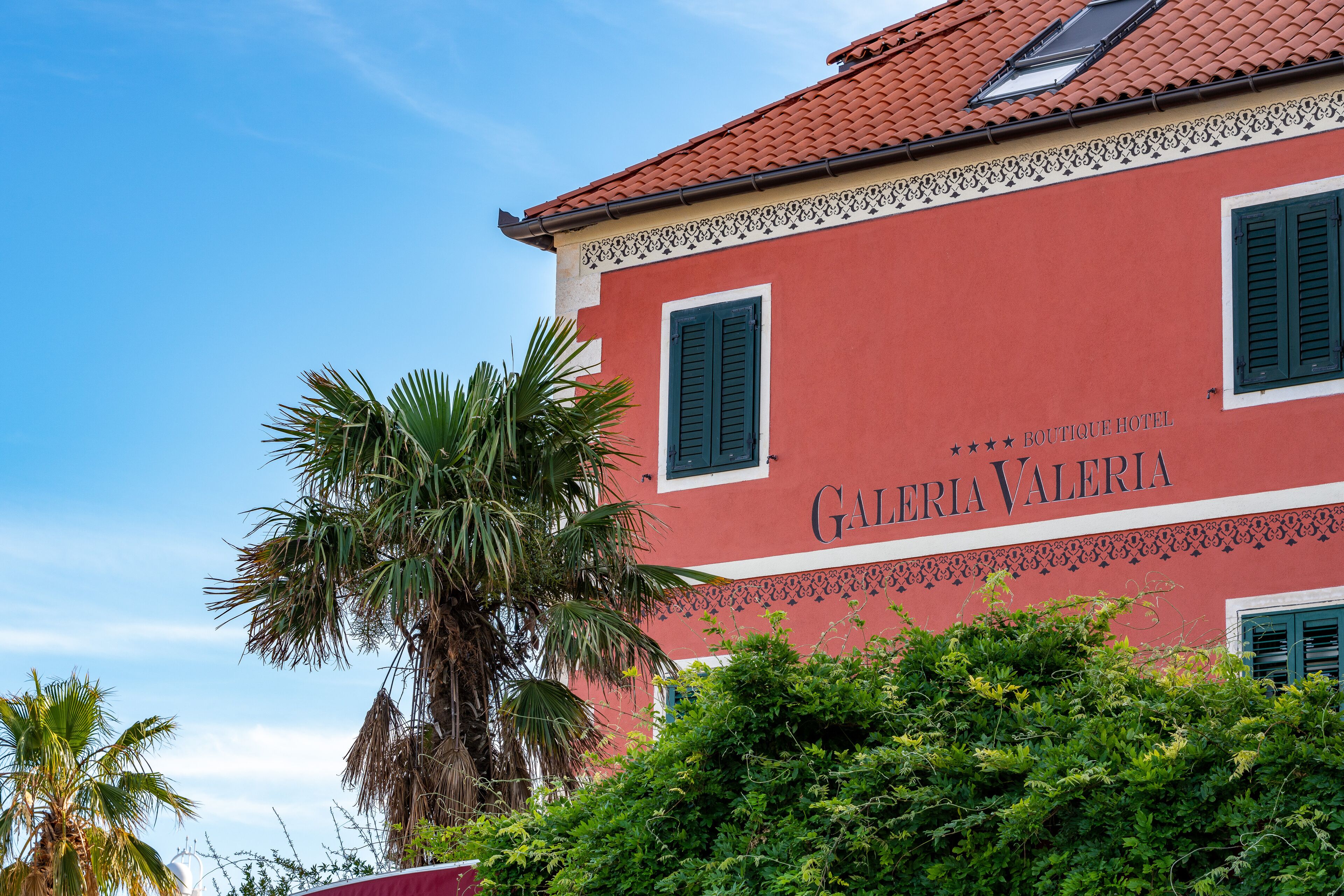 A red building with the sign "Galeria Valencia" and green shutters.