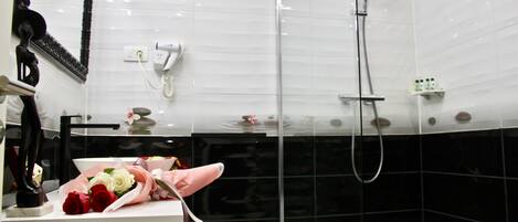 A bathroom with a white sink, a mirror, a shower, and a towel rack.