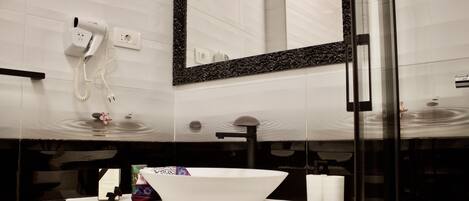A modern bathroom with a white sink, a large mirror, and a hairdryer mounted on the wall.