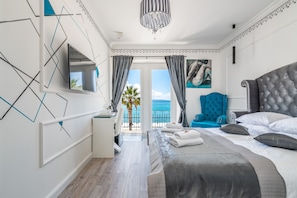 A modern bedroom with a large bed, a blue armchair, and a view of the sea. - Galeria Valeria Seaside Downtown - MAG Quaint & Elegant Boutique Hotel (Split)