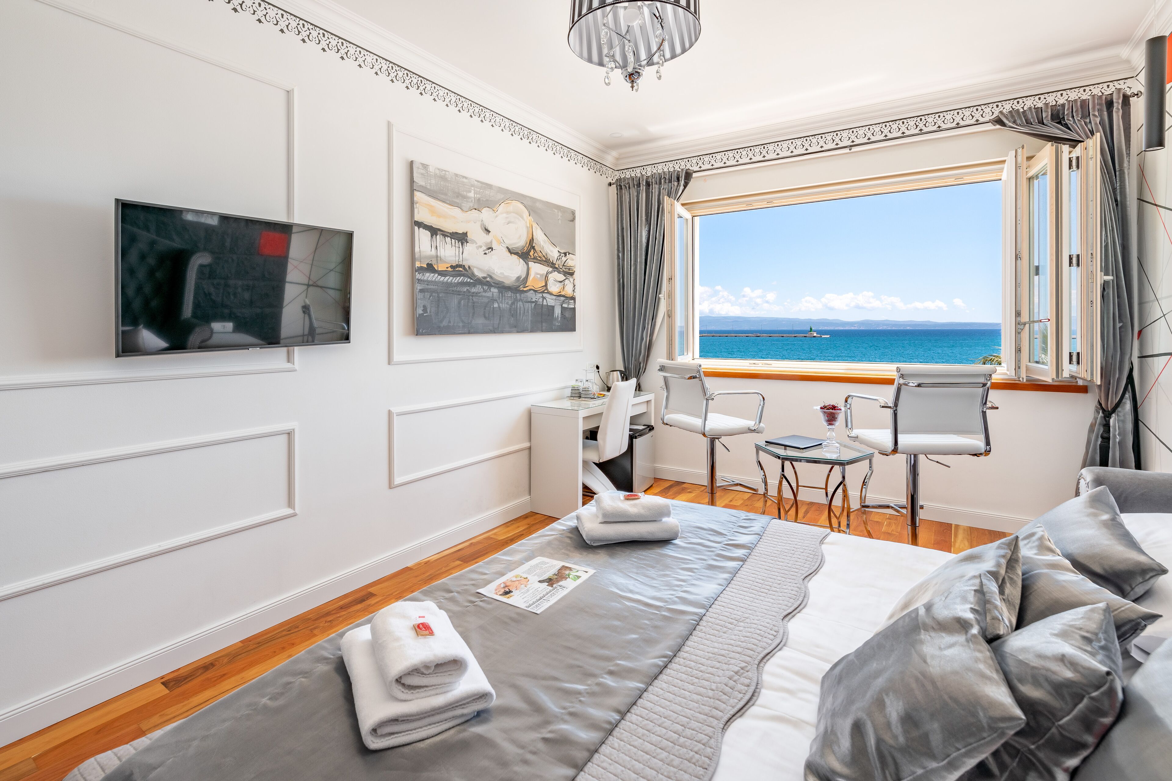 Habitación de hotel con cama, escritorio, silla y vista al mar.