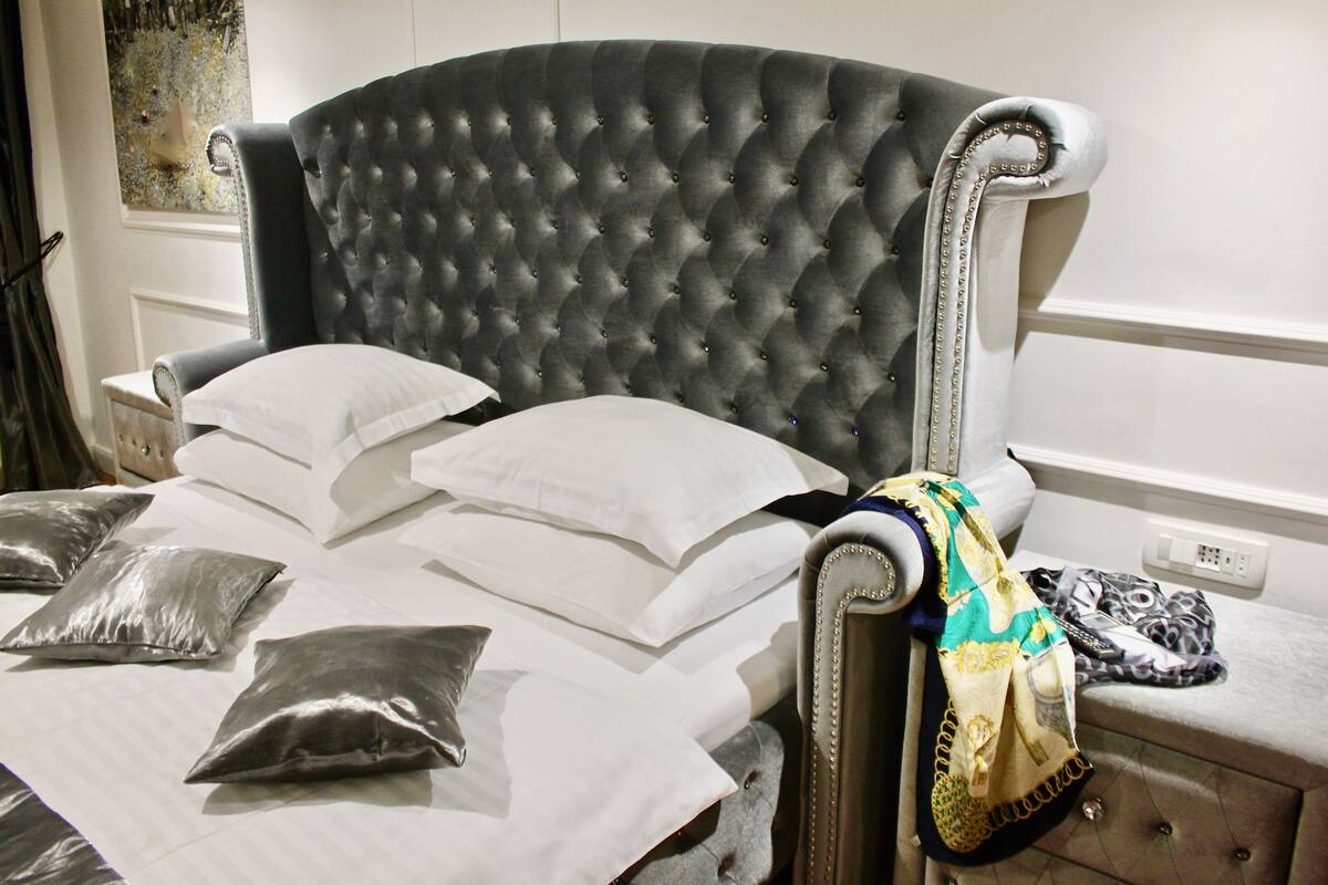 A neatly made bed with a tufted headboard, pillows, and a blanket.
