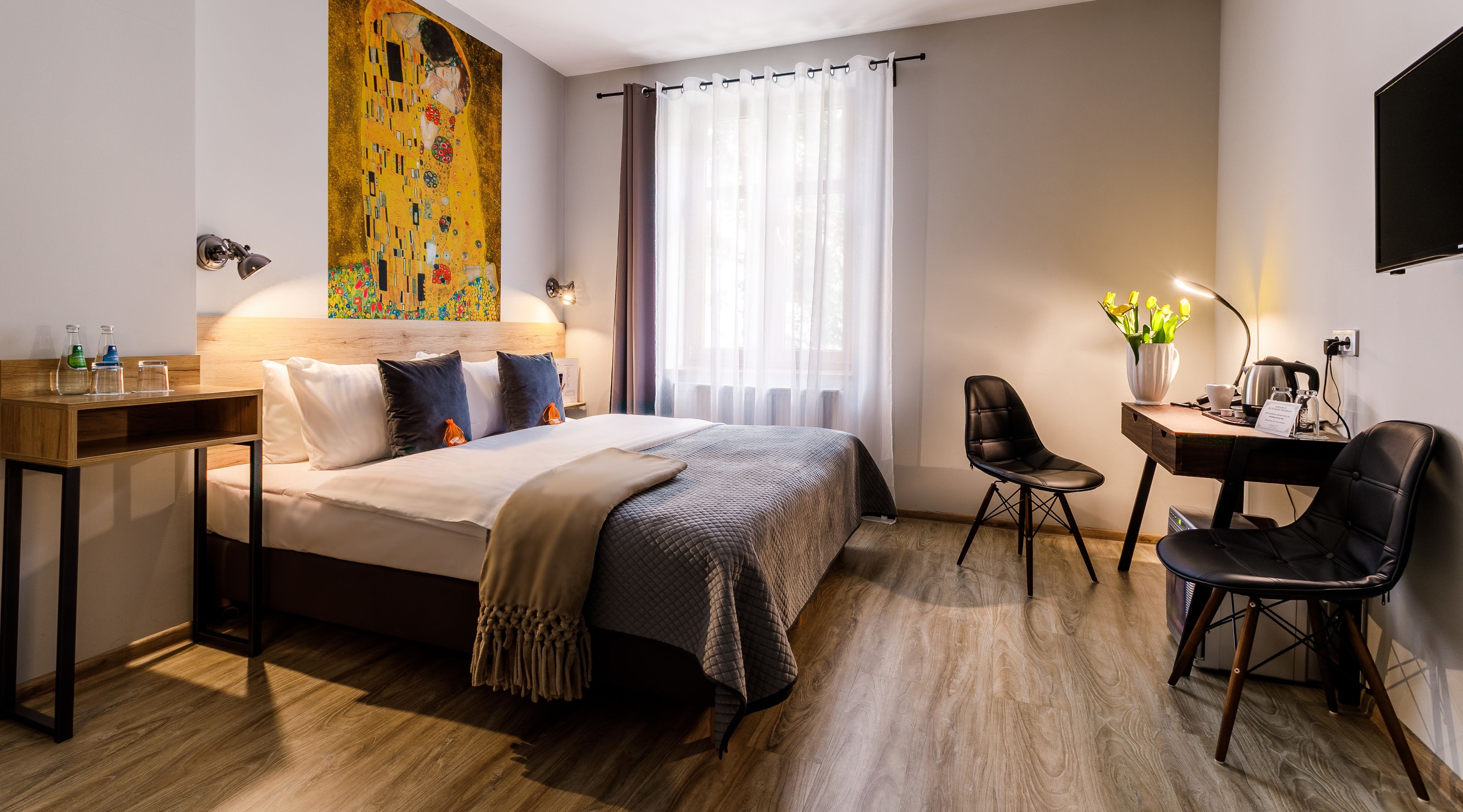 Una habitación de hotel moderna con una cama grande, un escritorio, una silla y un televisor.