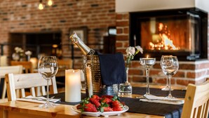 A dining table set with wine glasses, a candle, a bottle of champagne, and a plate of strawberries. - Art & Garden Residence (Kraków)