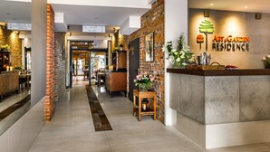 A hotel reception area with a brick wall, a reception desk, and directional signs. - Art & Garden Residence (Kraków)