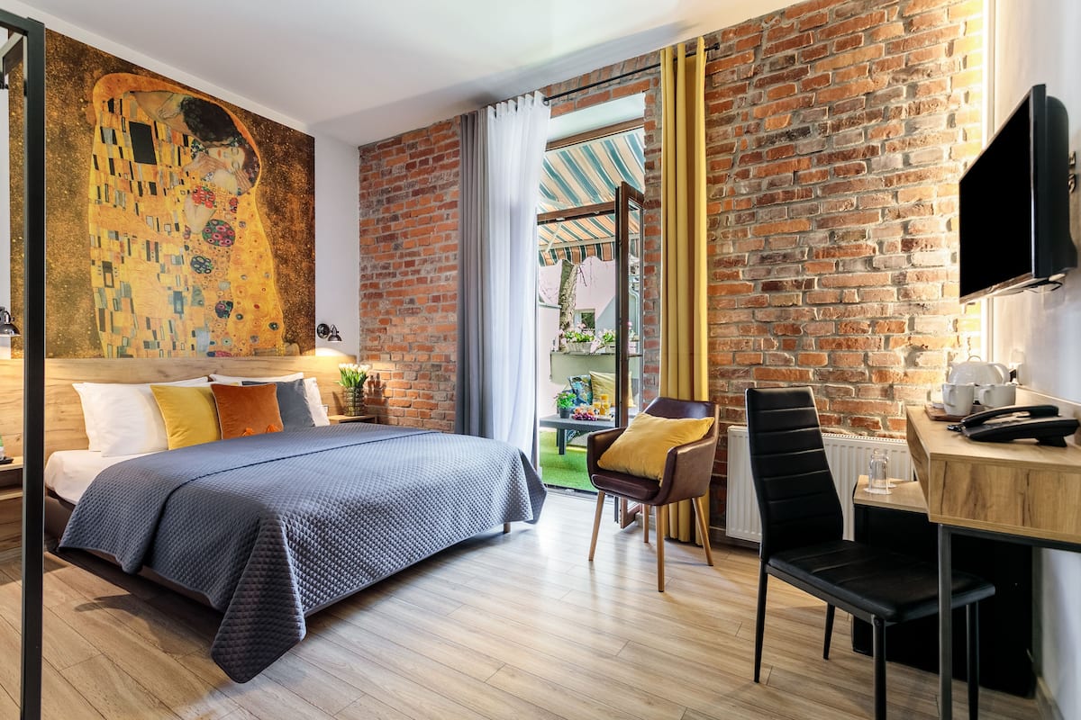A modern hotel room with a large bed, a desk, a chair, and a TV.