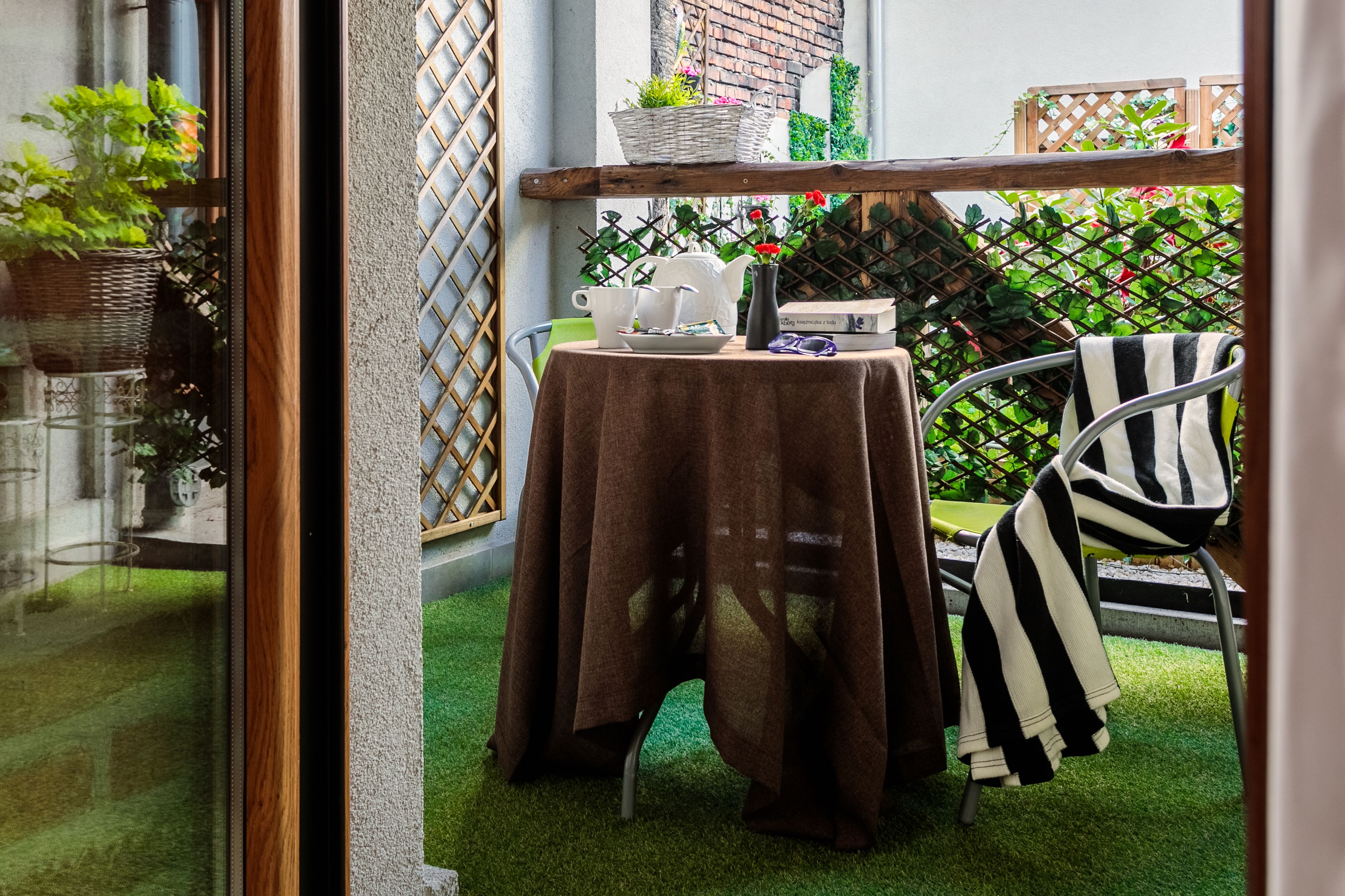 Un petit espace patio avec une table dressée pour deux personnes, une chaise et une serviette à rayures.