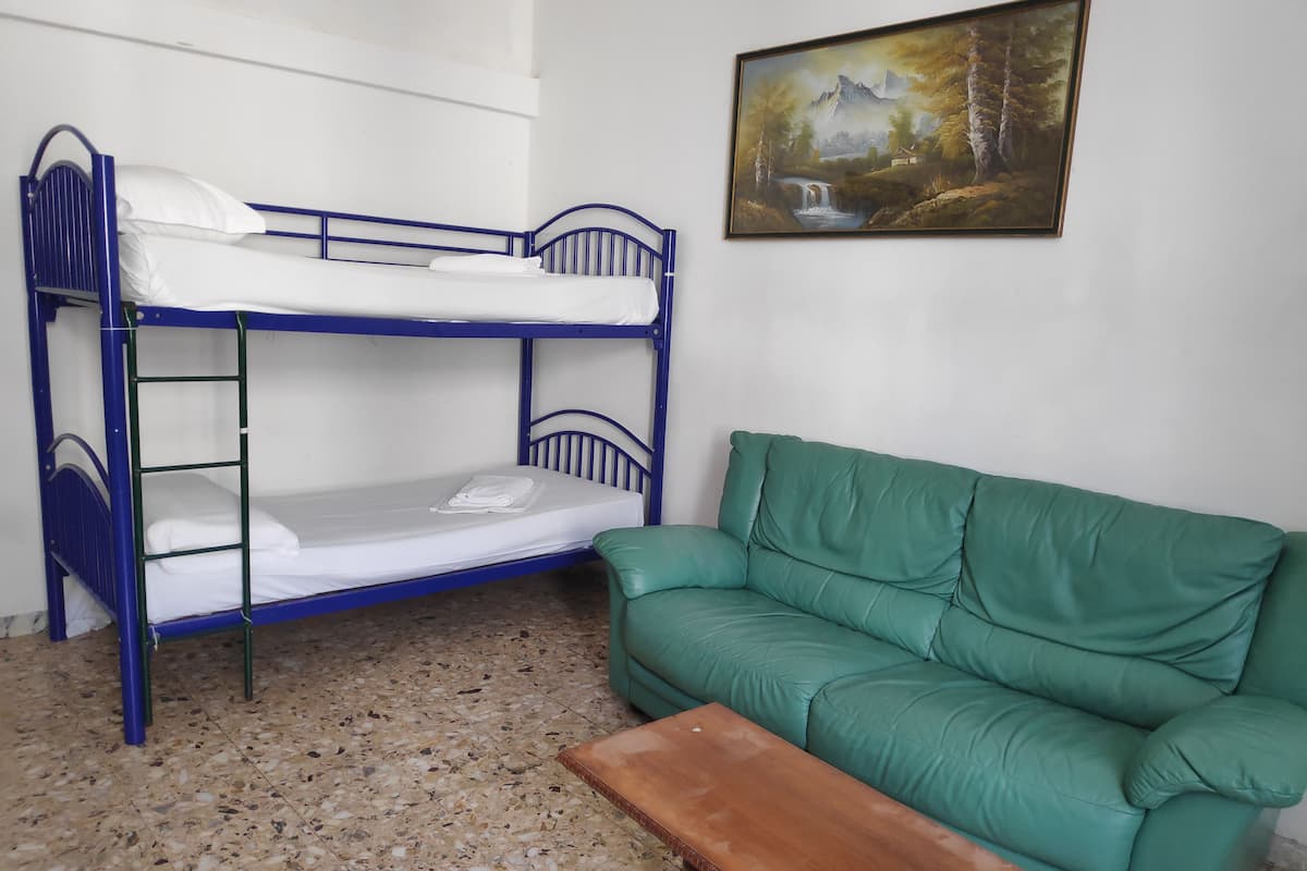 Un lit superposé avec un canapé vert et un tableau accroché au mur.