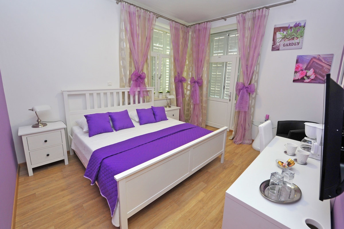 A neatly arranged bedroom with a bed, bedside tables, a desk, and a chair.