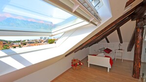 A bedroom with a skylight, a bed, a bedside table, and a view of the city. - Nirvana Luxury Rooms (Split)