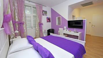 A bedroom with a bed, a TV, a desk, and a chair.