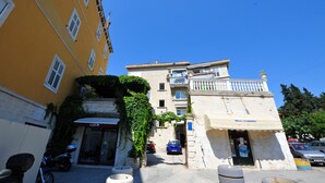 A street view with a yellow building, a blue car, and a motorcycle parked in front. - Nirvana Luxury Rooms (Split)