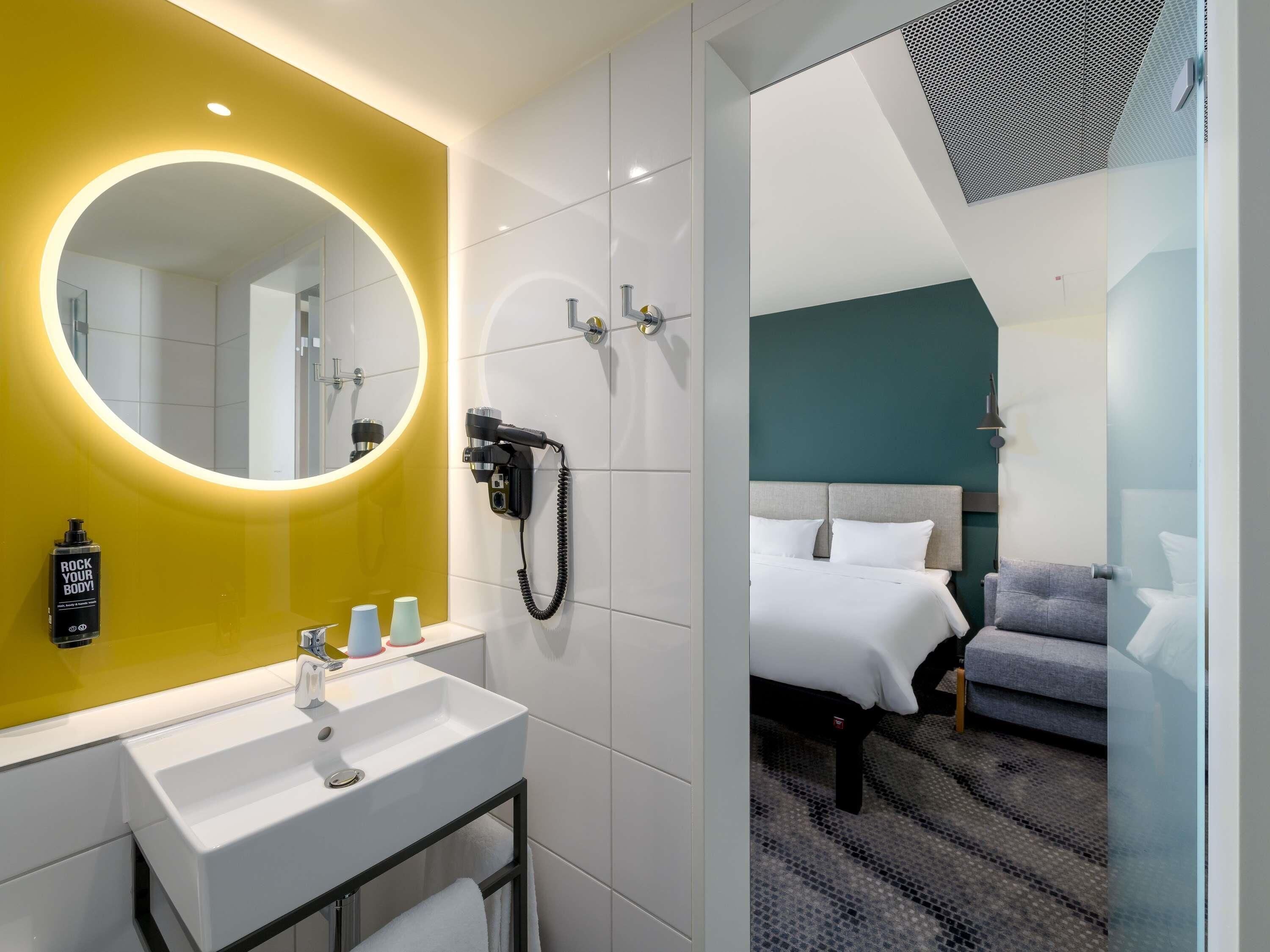 Een moderne hotelkamer met een badkamer, een bed en een spiegel.