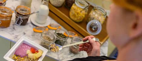 Une personne tenant un bol de yaourt aux fruits, agrémenté de granola.