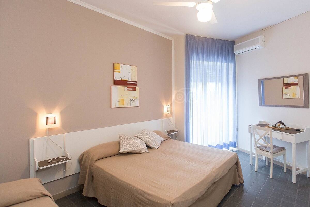 Ein Hotelzimmer mit Bett, Nachttischen, Schreibtisch und Stuhl.
