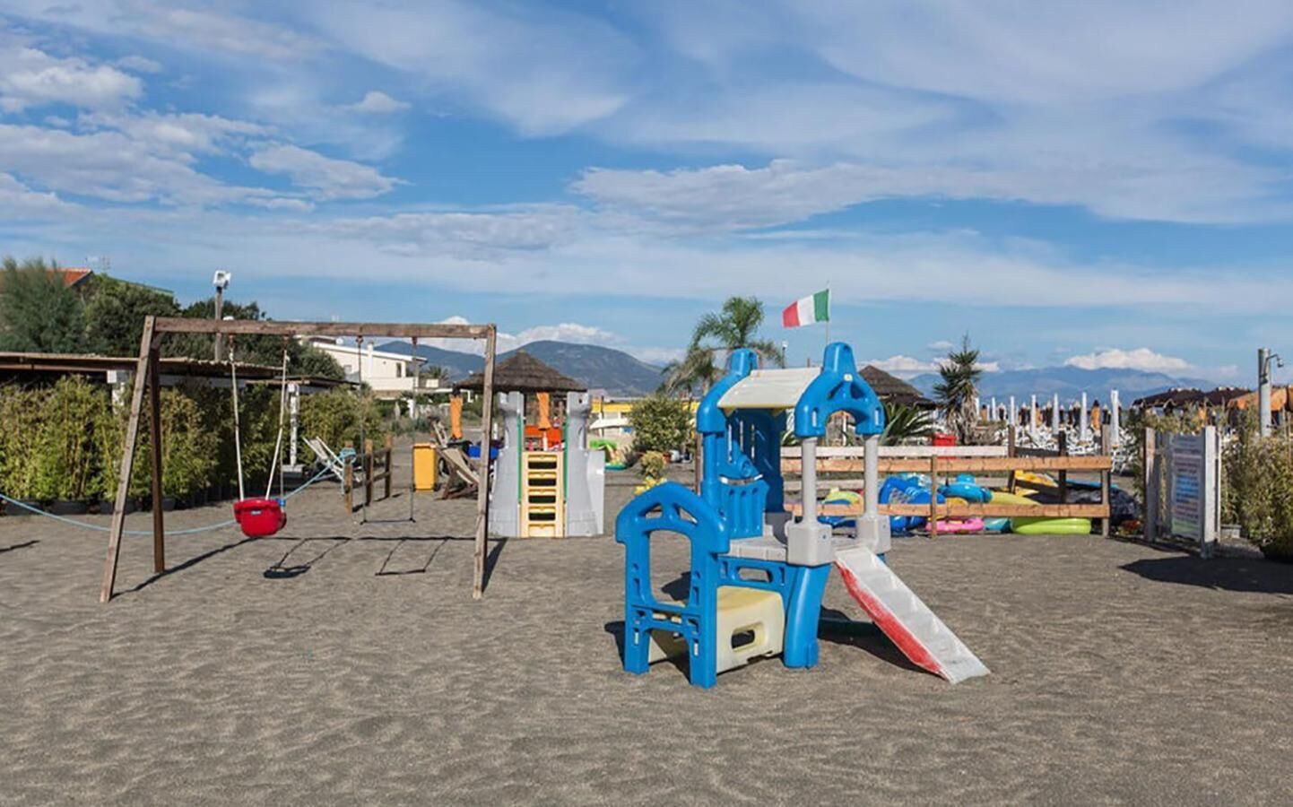 Un'area giochi con altalene, strutture per arrampicarsi e uno scivolo.