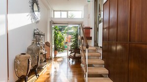 A hallway with a wooden staircase, a mirror, and pottery on shelves. - Hotel Anna (Terracina)