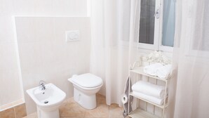 Ein Badezimmer mit Toilette, Bidet und einem Ablagefach mit Handtüchern.