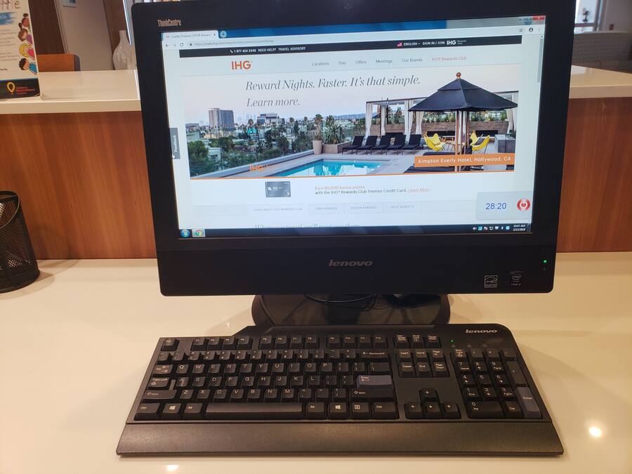 Een Lenovo monitor waarop een webpagina voor IHG Rewards Club wordt weergegeven, met uitzicht op een zwembad.