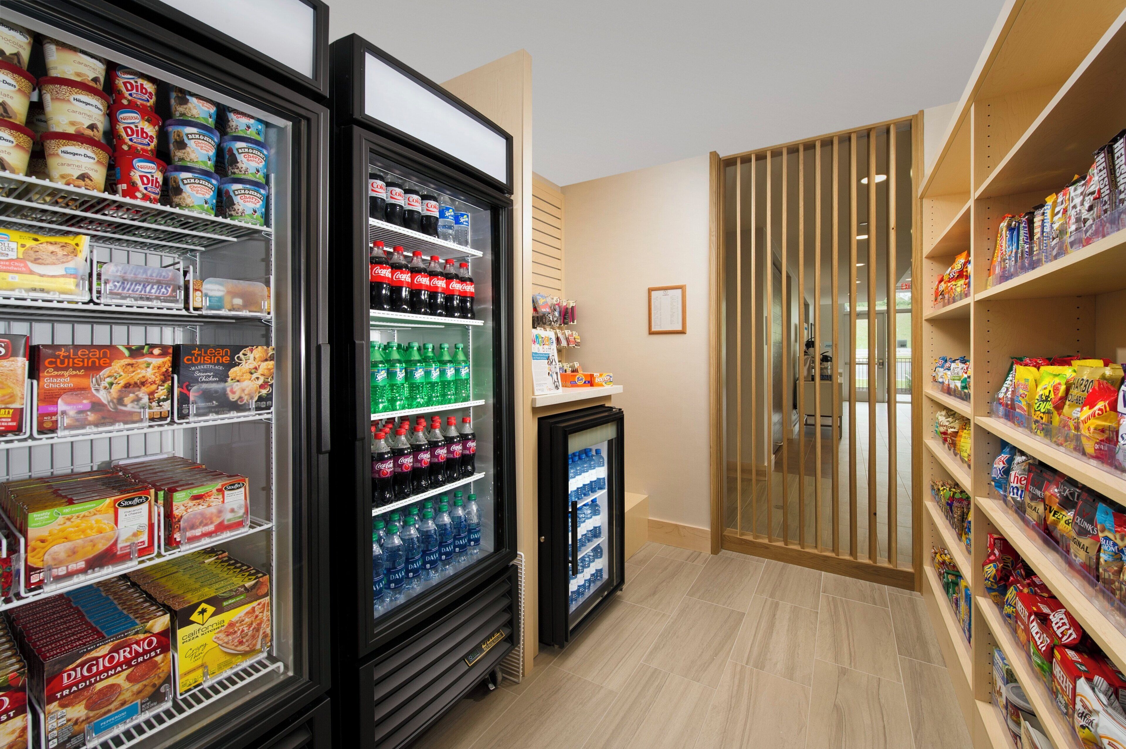 Un rayon réfrigéré où sont proposés divers produits alimentaires et boissons, notamment des glaces, des sodas et de l’eau en bouteille.