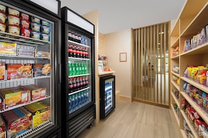 Seção refrigerada com diversos alimentos e bebidas, incluindo sorvete, refrigerante e água engarrafada.