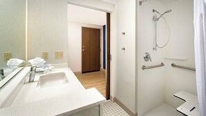 Un baño moderno con lavamanos, espejo y ducha blancos.