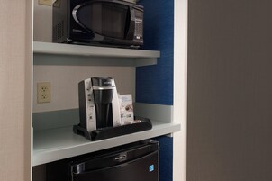 Una kitchenette equipada con microondas, cafetera y refrigerador pequeño.
