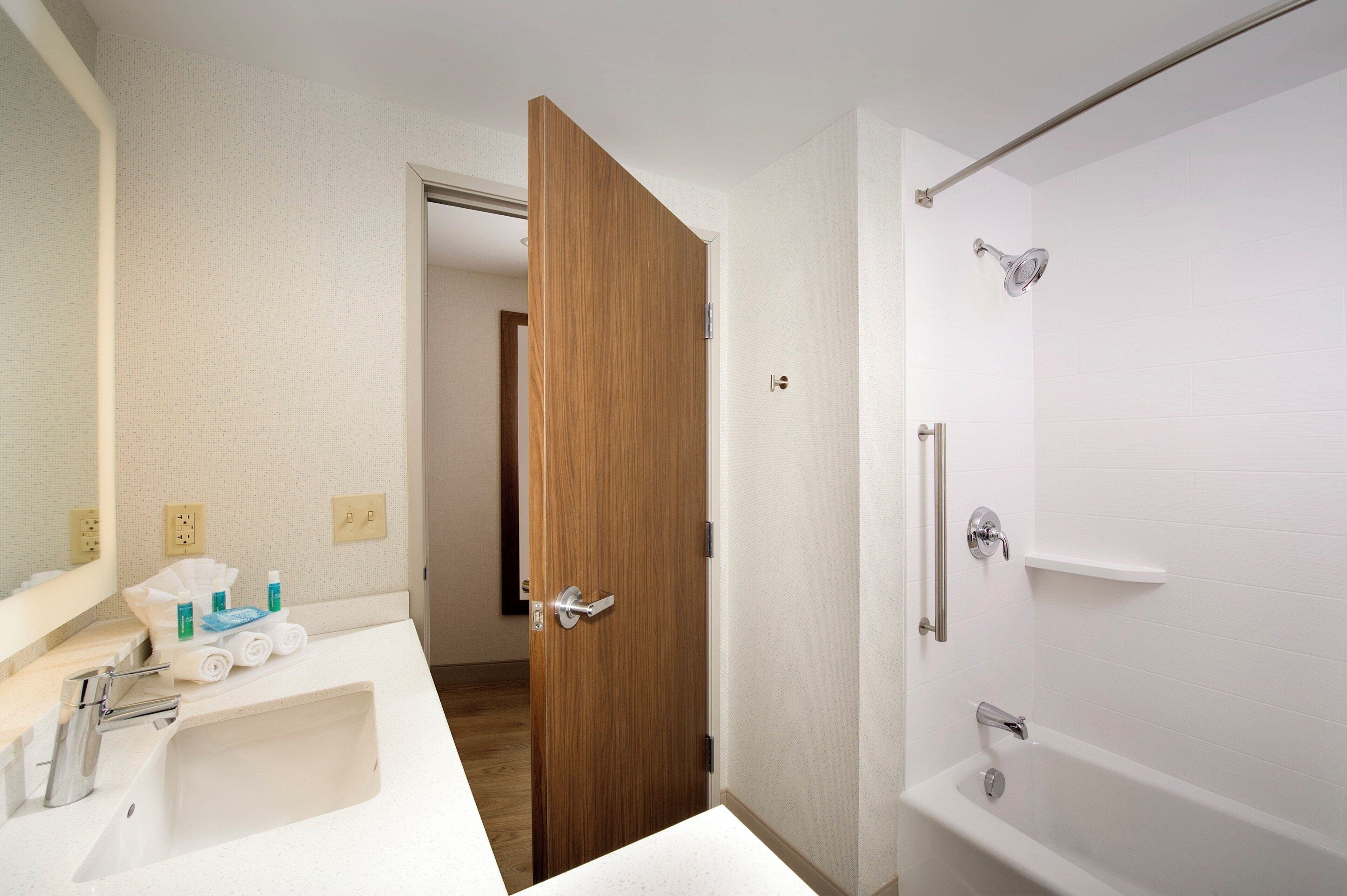 Een badkamer met een witte wastafel, spiegel en een douche met een glazen deur.