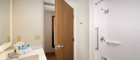 Un baño con lavamanos blanco, espejo y ducha con puerta de vidrio.