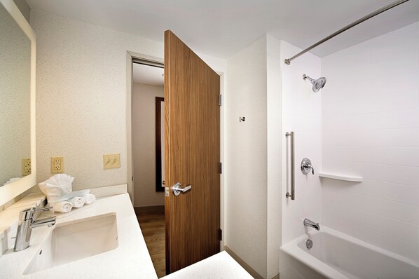 A bathroom with a white sink, a wooden door, a shower with a glass door, and a mirror. - Holiday Inn Express & Suites Altoona by IHG (Altoona)