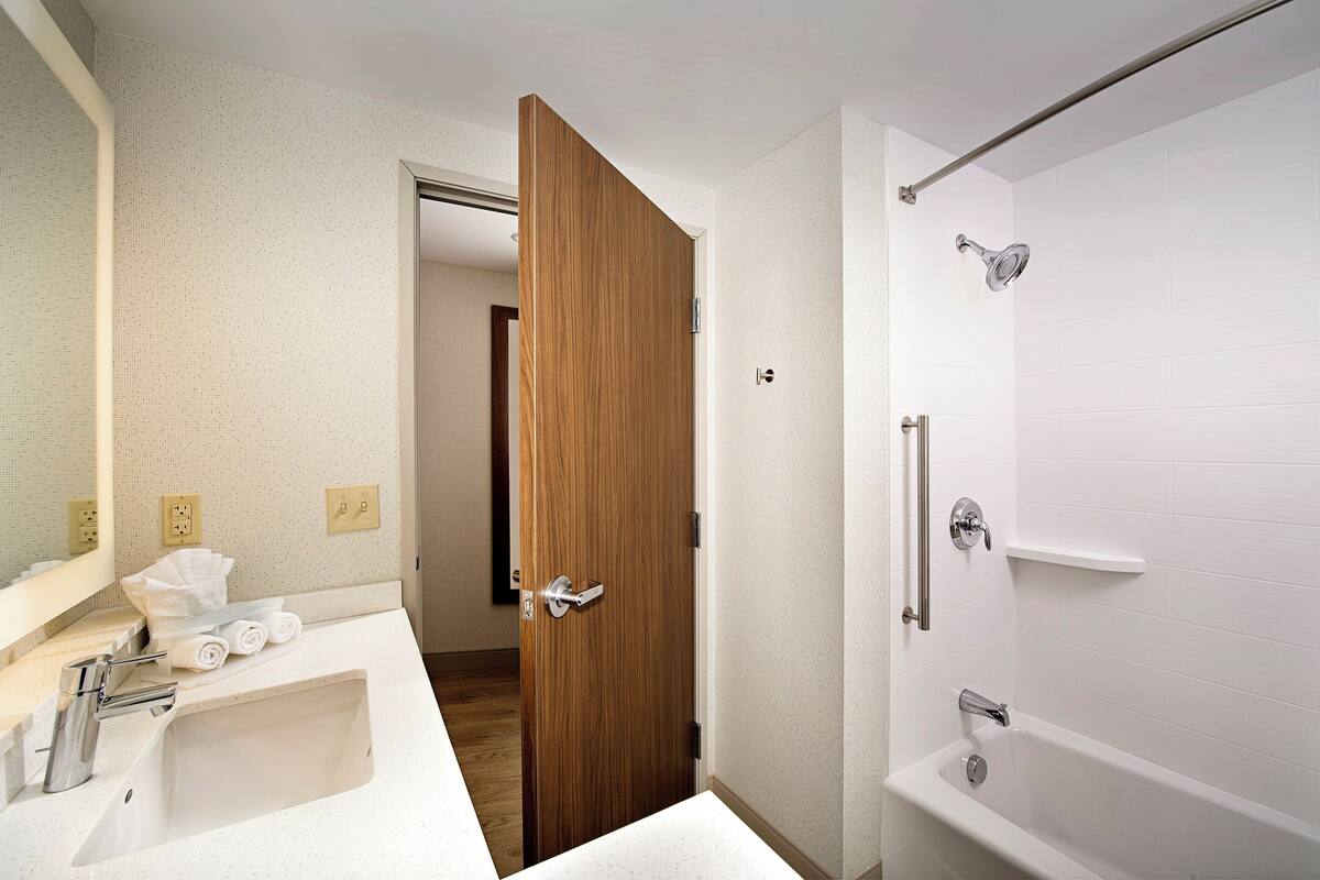 Un baño con lavamanos blanco, espejo y ducha.