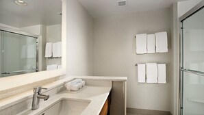 Un baño moderno con un espejo grande, un lavabo y una zona de ducha.