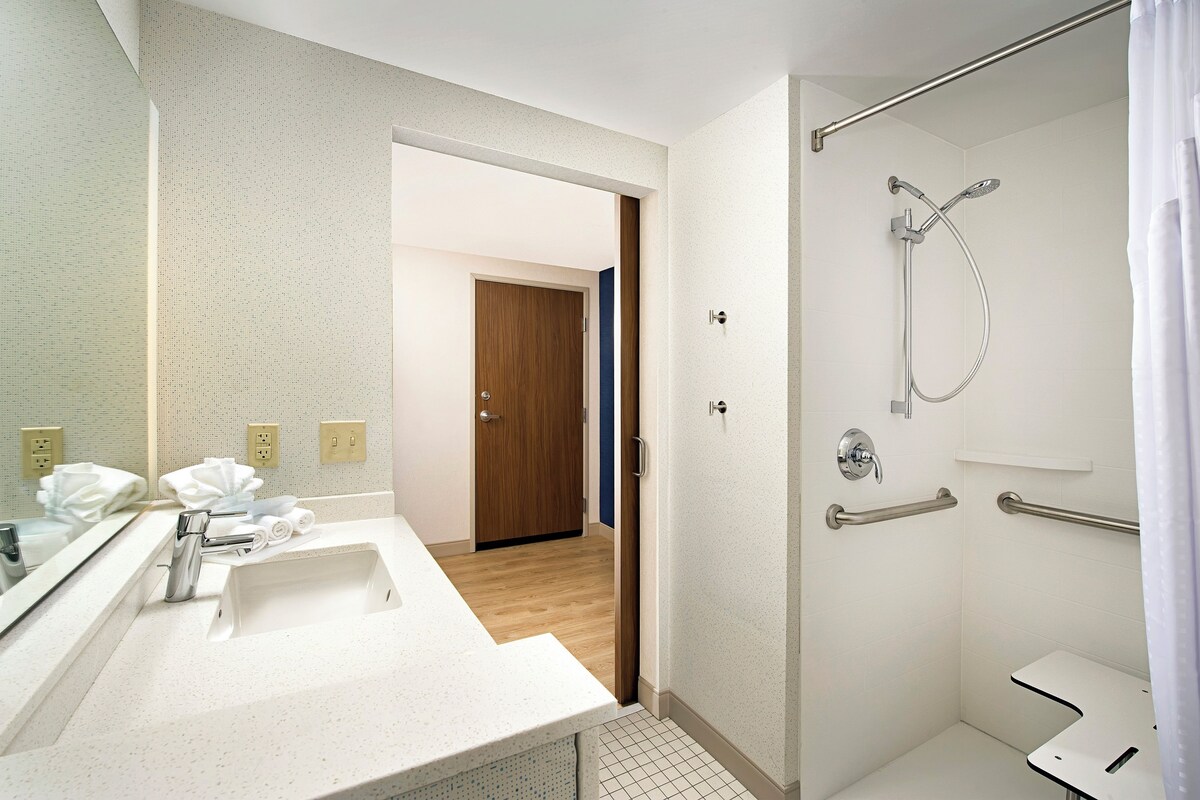 A modern bathroom with a shower, a sink, and a mirror.