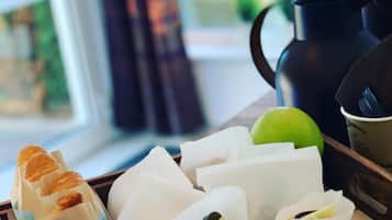 A tray with sandwiches, a green apple, and a coffee pot.