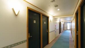 A hotel corridor with carpeted floors, wooden doors, and a light-colored wall with a decorative border. - Toyoko Inn Kumamoto Ekimae (Kumamoto)