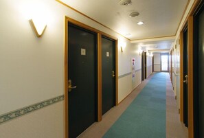 A hotel corridor with carpeted floors, wooden doors, and a light-colored wall with a decorative border. - Toyoko Inn Kumamoto Ekimae (Kumamoto)