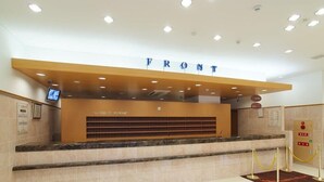 A reception desk with a 'FRONT' sign above it, a digital screen, and a yellow rope barrier. - Toyoko Inn Kumamoto Ekimae (Kumamoto)