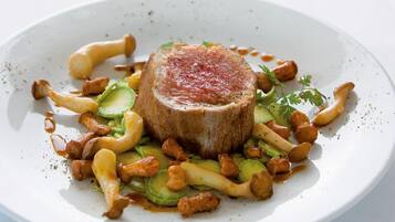 A plate of food with a central piece of meat, surrounded by vegetables and mushrooms.