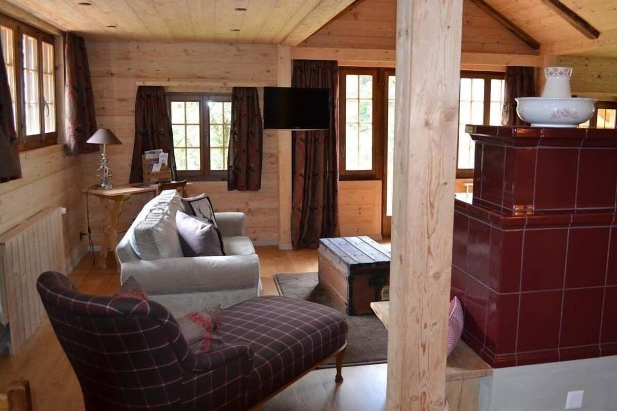 A cozy cabin interior with a sofa, a television, and a fireplace.