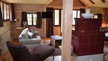 A cozy cabin interior with a sofa, a television, and a fireplace.