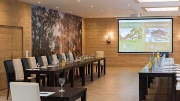 A conference room with a long table and chairs, a projector screen displaying text, and a mural on the wall.