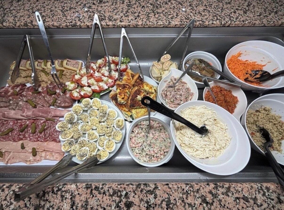 A buffet with various food items including meats, salads, and pasta dishes.