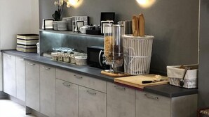 Ett modernt kök med gråa skåp, en inbyggd kaffemaskin och en bänkskiva med diverse köksredskap.
