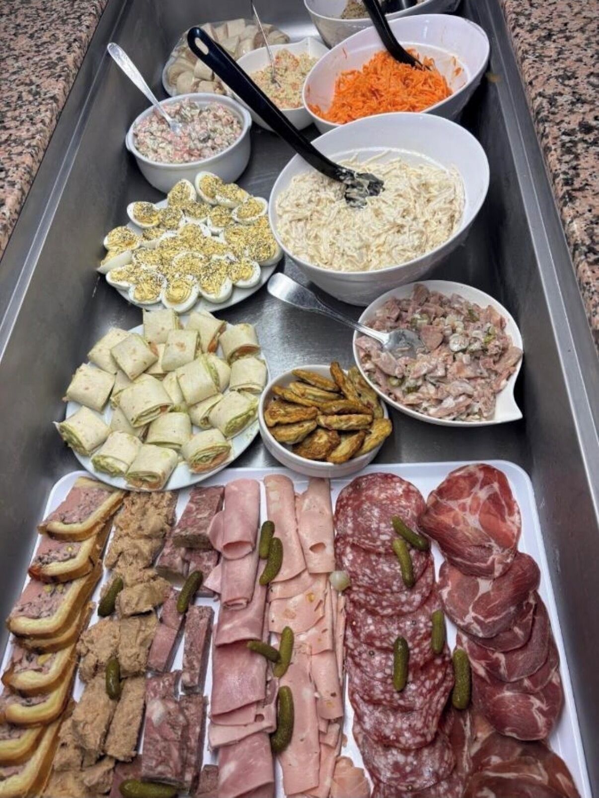 Ein Buffet mit verschiedenen Speisen, darunter Fleisch, Salate und Dips.
