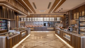 A modern breakfast bar with wooden paneling and a checkered floor, featuring various food stations and a central counter. - Melas Resort Hotel (Manavgat)