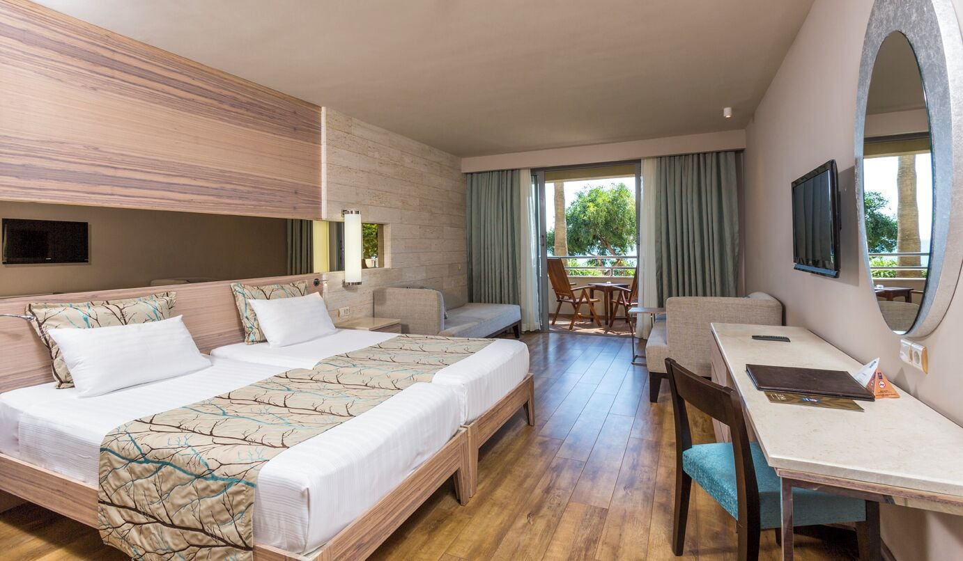 A hotel room with a bed, a desk, a chair, and a view of the outdoors.