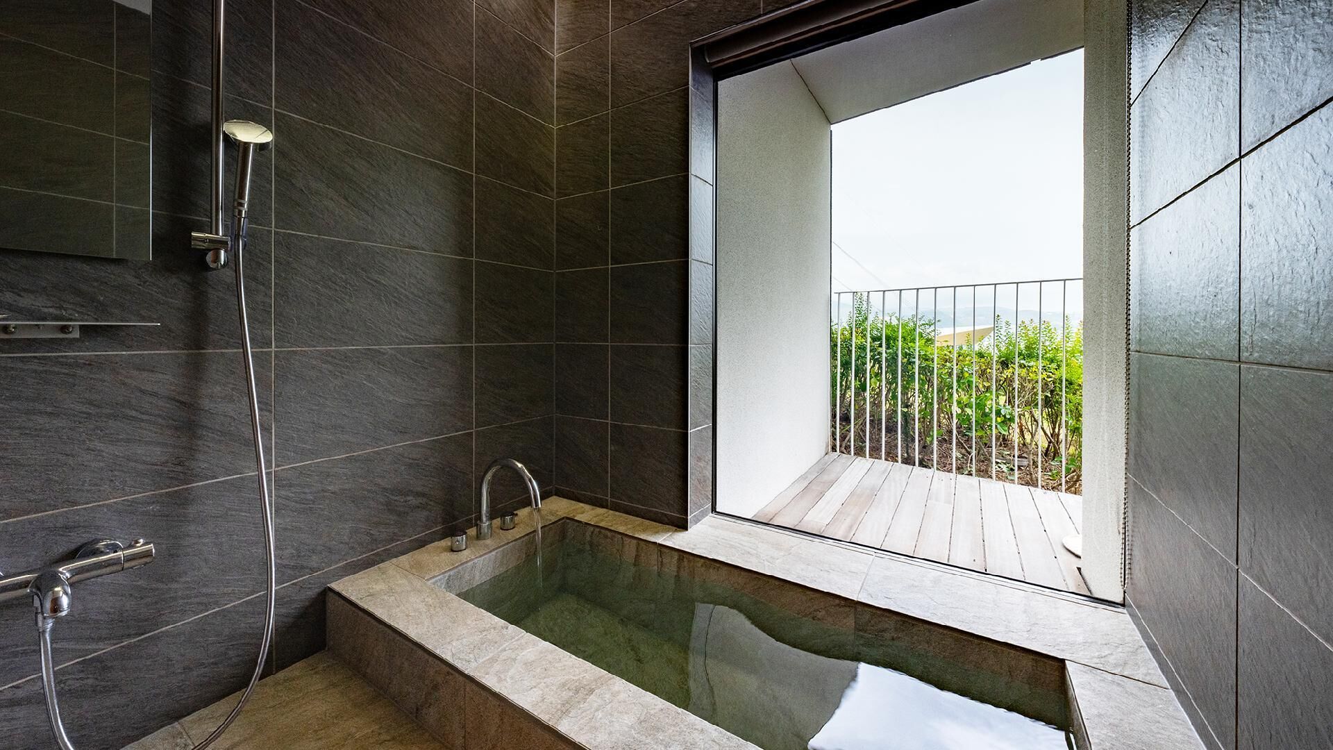 A modern bathroom with a bathtub, a shower, and a balcony with a view.