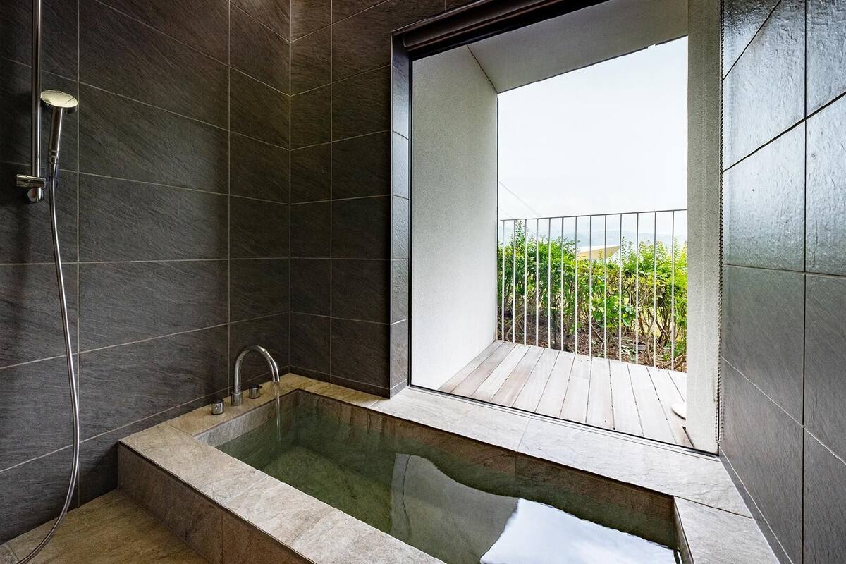 A modern bathroom with a bathtub, a shower, and a balcony with a view.
