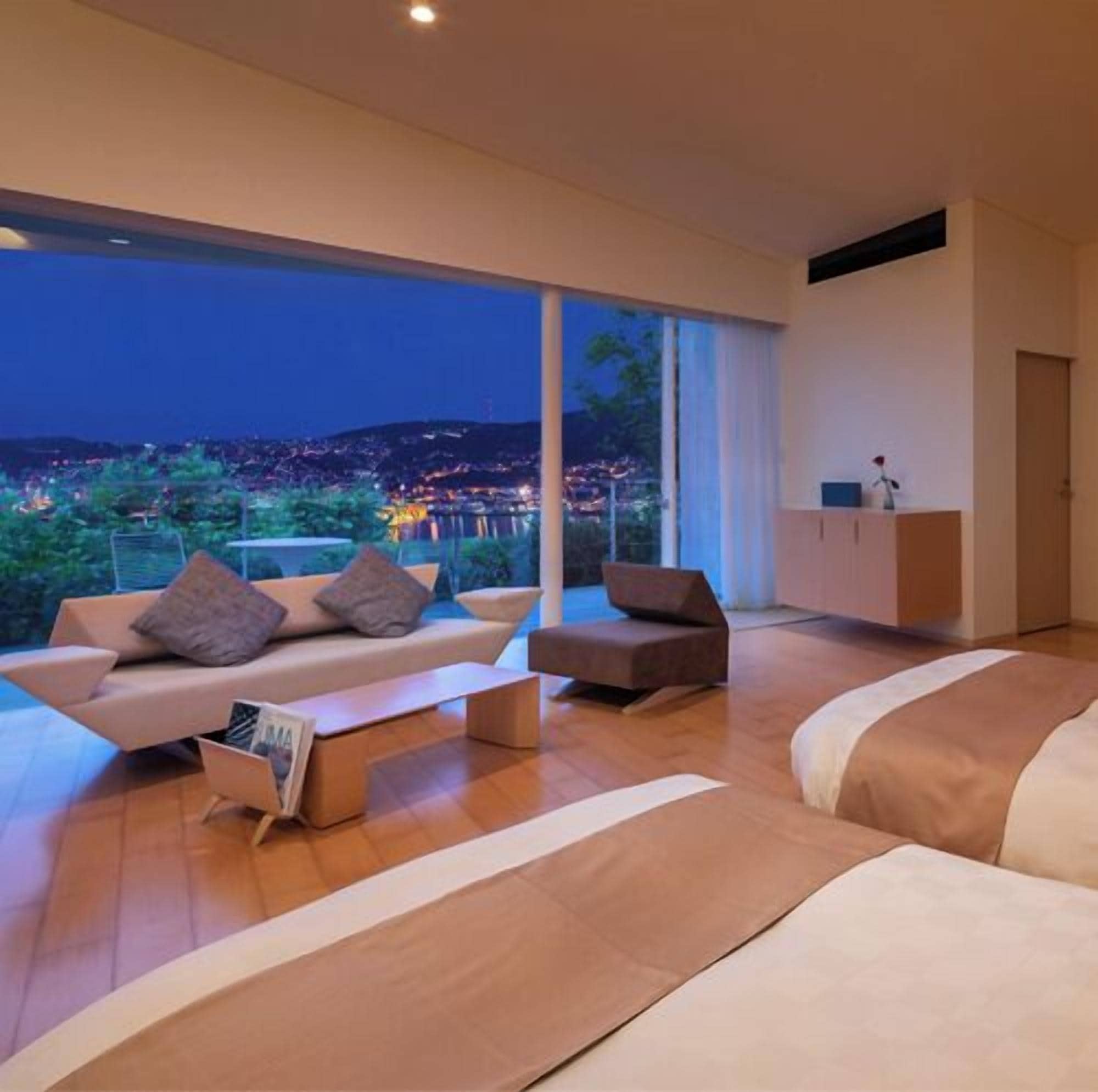 A modern bedroom with a large window, a sofa, a chair, and a bed.