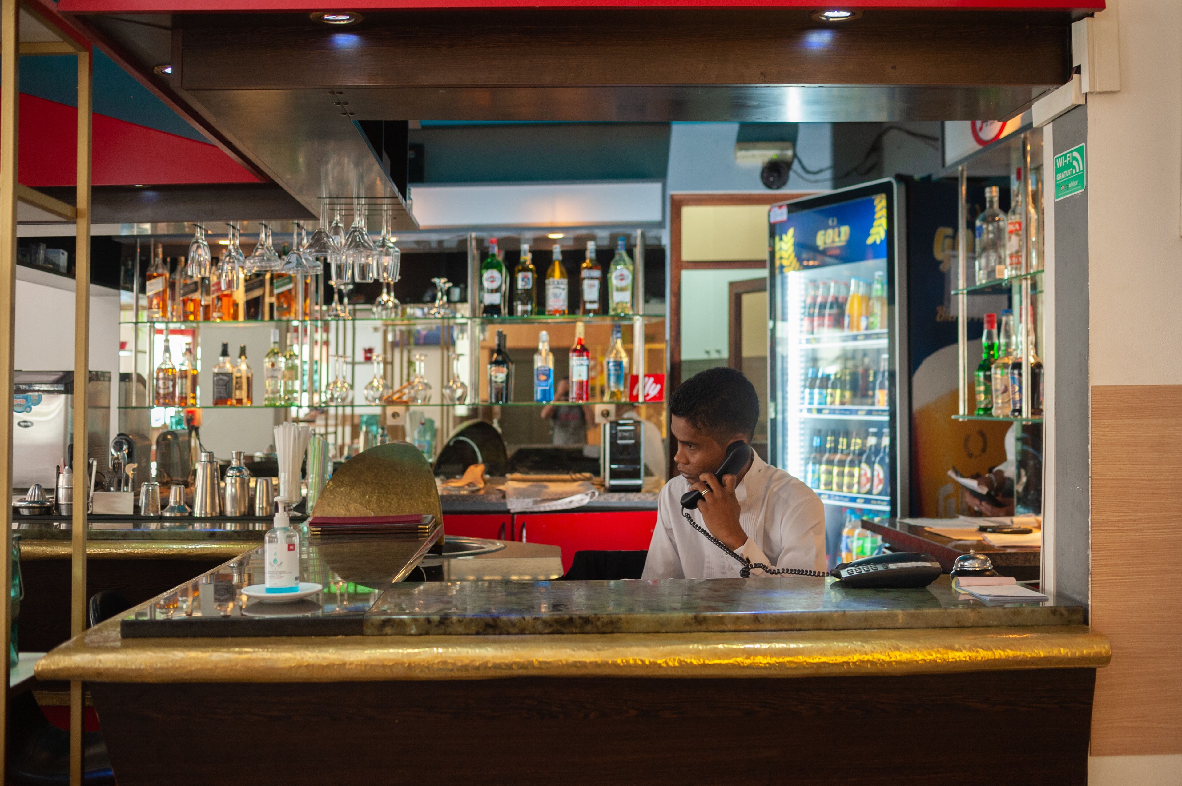 A bar area with a counter, various bottles, and a refrigerator.